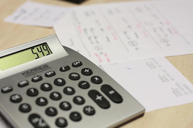 Bild på en grå miniräknare med pappers fakturor i bakgrunden.